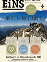 Das Cover des Magazins "EiNS" zeigt eine Gruppe von Menschen, die auf einem Berggipfel stehen und in die Ferne blicken. Der Titel "Mutig in die Zukunft" ist prominent platziert. Darunter sind drei Symbole: ein Herz, ein Buch und eine Mission. (Text KI generiert)